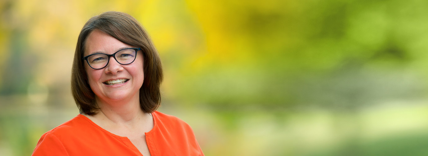 Employee portrait outdoors with a blurred green natural background, representing staff like at Milaca Elim Meadows