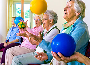Group of older adults seated and participating in an exercise class using colorful balls, representing strength, balance, and mobility programs like at Milaca Elim Meadows