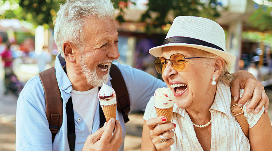 Two older adults holding ice cream cones while standing close together outdoors, representing social connection and enjoyable activities like at Milaca Elim Meadows