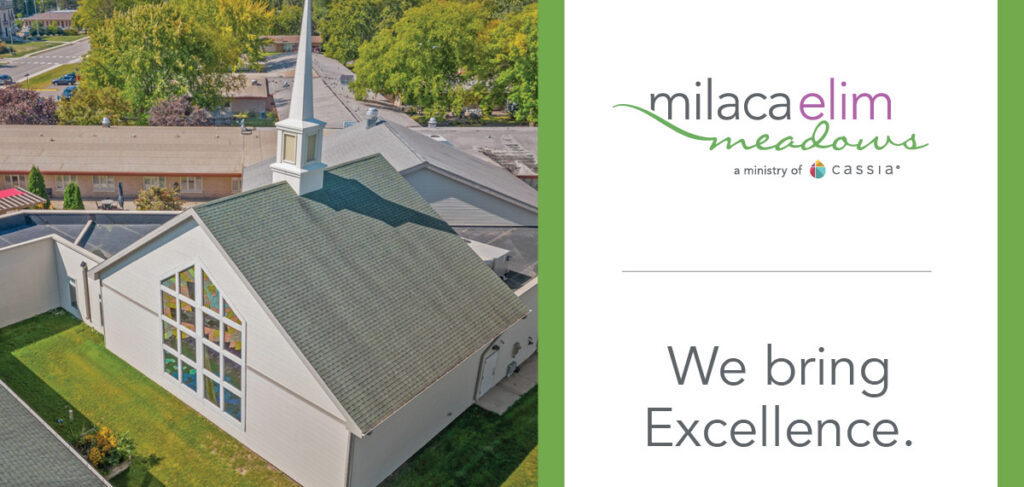Aerial view of the chapel at Milaca Elim Meadows, featuring a steep roof, white steeple, and large stained-glass window, surrounded by green lawns and trees, alongside branding that reads “Milaca Elim Meadows” and “We bring Excellence.”