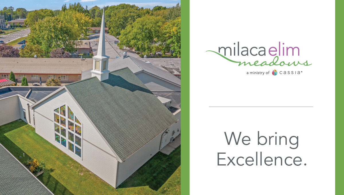 Aerial view of the chapel at Milaca Elim Meadows, featuring a steep roof, white steeple, and large stained-glass window, surrounded by green lawns and trees, alongside branding that reads “Milaca Elim Meadows” and “We bring Excellence.”