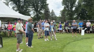 Golfers and volunteers gather near the clubhouse before the 2026 Milaca Elim Meadows Golf Classic at Stones Throw Golf Course.