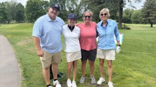 Five golfers pose together on the green during the 2026 Milaca Elim Meadows Golf Classic at Stones Throw Golf Course.